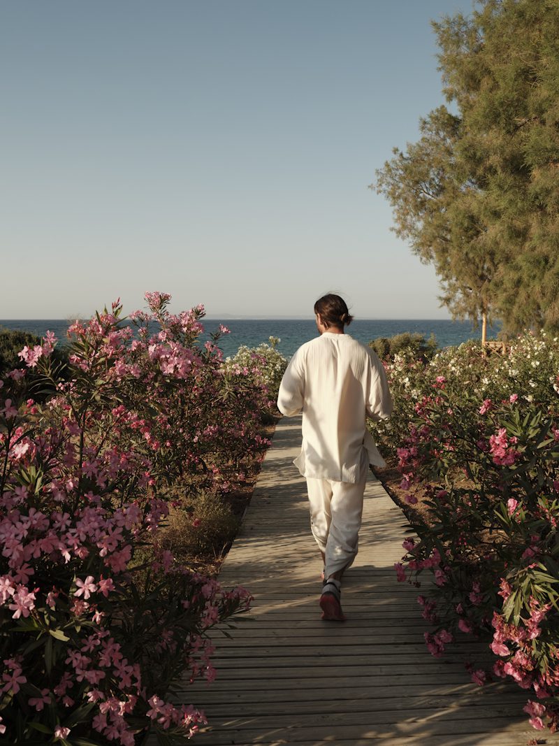 Man walking through blooming oleanders toward the sea at Banana Baya Zakynthos